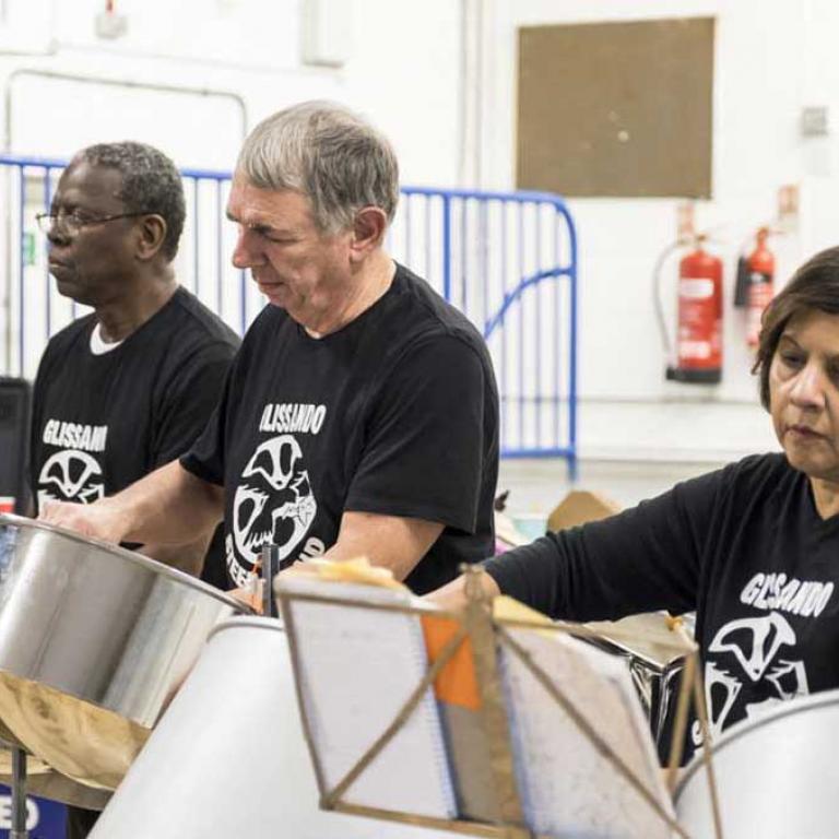 Photo depicts two male members and two female members of the Glissando Steel Band playing their drums at the Wornington Word launch