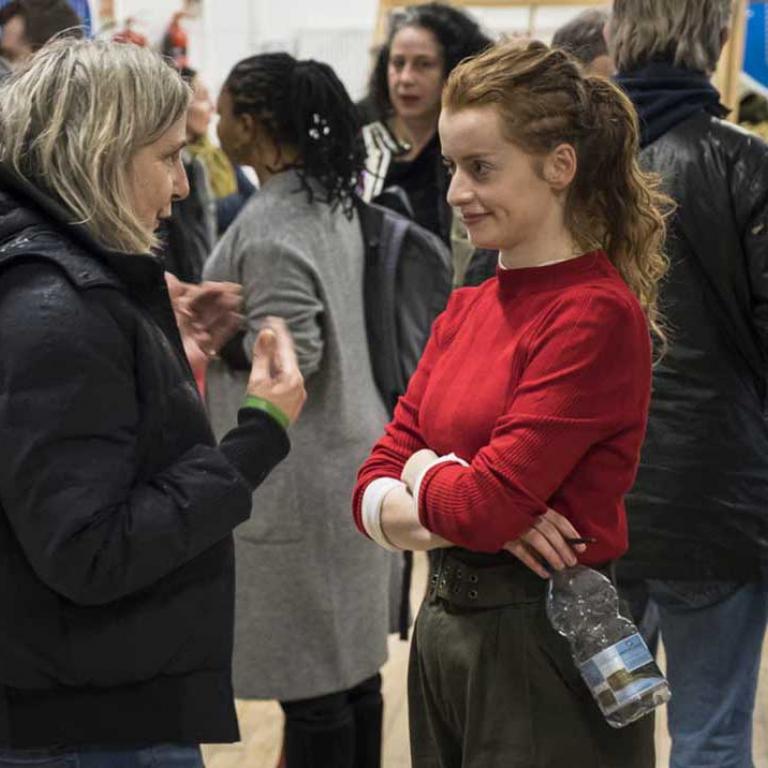 Photo depicts Hannah Hutch talking to a woman in the foreground, in the background are residents and locals all of which are attending the Wornington Word launch at the Venture Centre