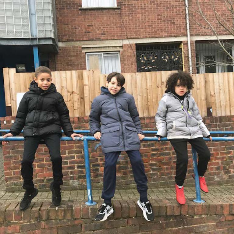 Khy, Marcus and Levee sit on the blue railings outside the entrance to Watts House on a break from shooting the short film The Seeker. Photo by Natasha Langridge