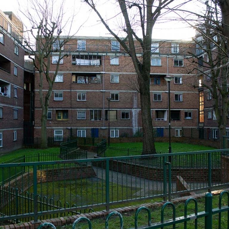The garden square at the centre of Katherine House, Macaulay House and Breakwell Court.  There are four large trees without leaves at the heart of the green grassy square. Photo from Wornington Road by Constantine Gras, local film maker.