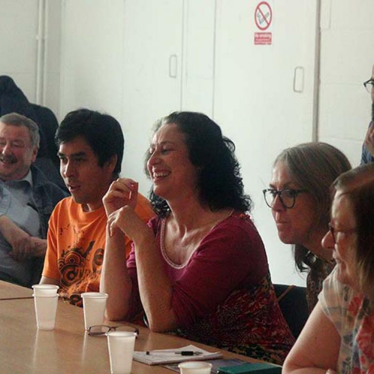 Film Making workshop taking place inside Venture Community Association. Participants are laughing as they learn about camera angles and mise en scene as instructed by Sanya Mihaylovic. From left to right: Keith Stirling, Jonathan Franco, Natasha Langridge, Caroline Moss, David Saiz and Margaret Cairns-Irvin. Photo taken by Darnell Da Costa 2019.
