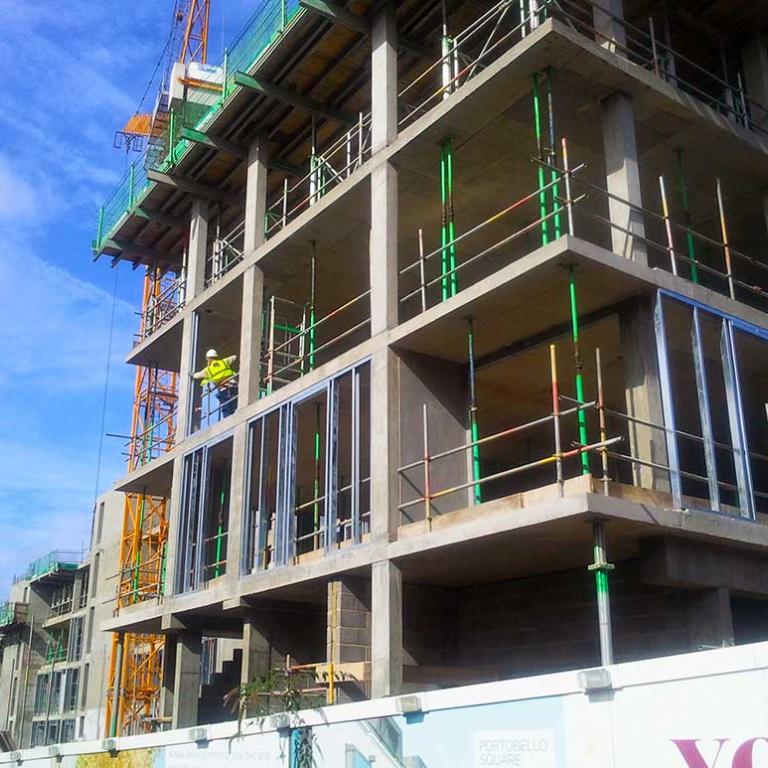 The new builds of Portobello Square on Faraday Road being constructed. A builder leans on a scaffold support between the concrete floors and support walls. In the background are two cranes. Photo by Junior Tomlin, 2014.